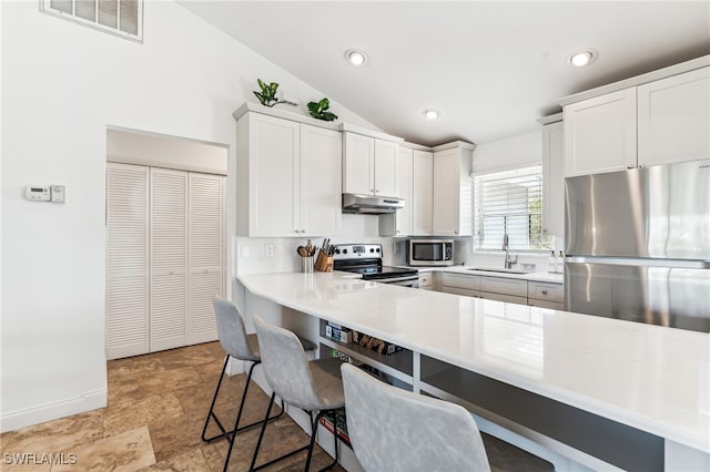 kitchen with stainless steel appliances, vaulted ceiling, kitchen peninsula, a breakfast bar, and white cabinetry