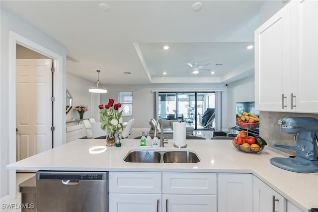 kitchen with a raised ceiling, hanging light fixtures, sink, white cabinets, and stainless steel dishwasher