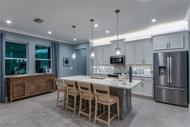 kitchen with appliances with stainless steel finishes, a kitchen bar, hanging light fixtures, sink, and a kitchen island with sink