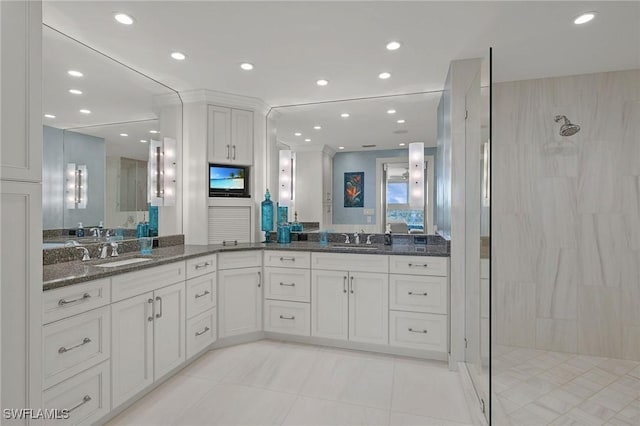 bathroom with a tile shower, vanity, and tile patterned floors