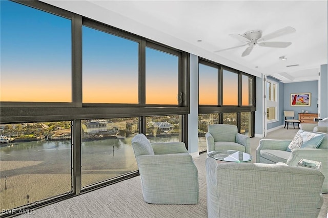 sunroom / solarium featuring a water view and ceiling fan