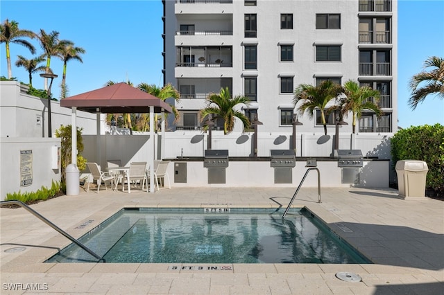 view of pool featuring exterior kitchen, a gazebo, and a patio area