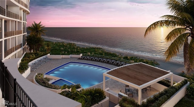 pool at dusk featuring a view of the beach, a water view, and a patio area