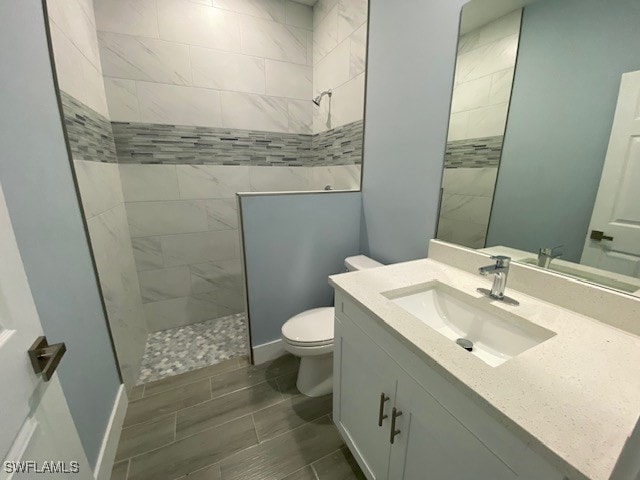 bathroom featuring vanity, toilet, and a tile shower