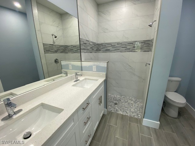 bathroom featuring vanity, toilet, and a tile shower