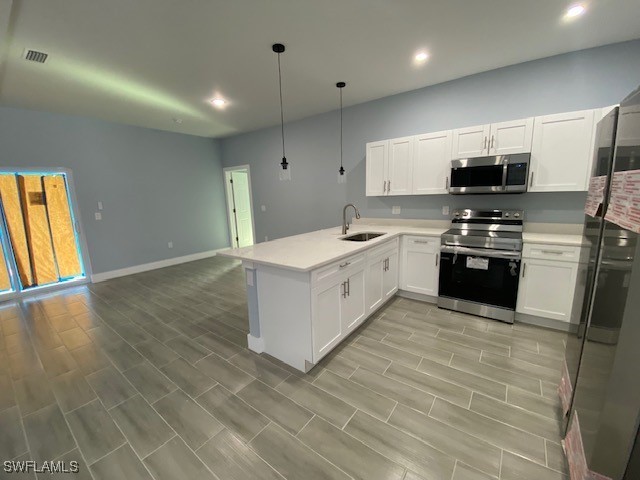 kitchen with stainless steel appliances, white cabinets, sink, and kitchen peninsula