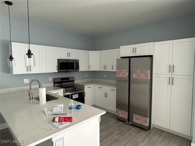 kitchen featuring pendant lighting, appliances with stainless steel finishes, white cabinets, and sink