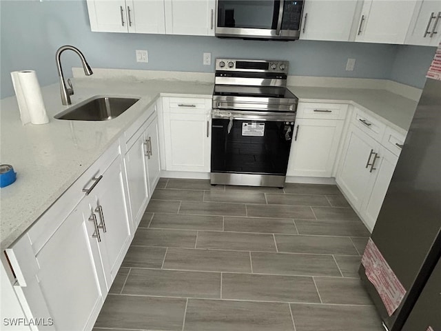 kitchen featuring white cabinets, sink, light stone counters, and stainless steel appliances