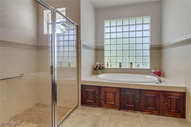 bathroom featuring independent shower and bath, tile patterned flooring, and tile walls