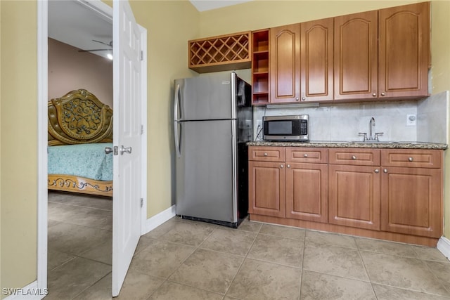 kitchen featuring backsplash, sink, light tile patterned floors, and stainless steel appliances