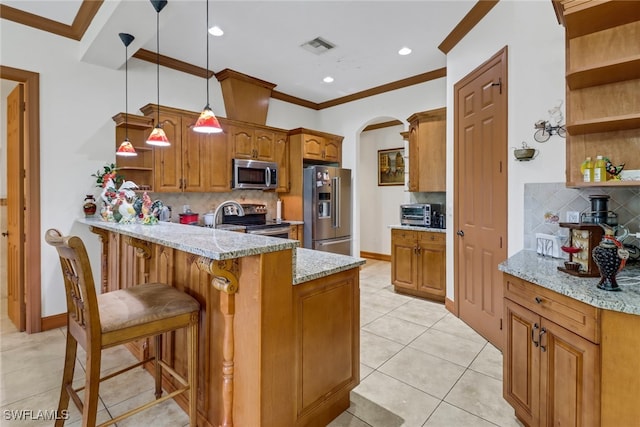 kitchen featuring tasteful backsplash, appliances with stainless steel finishes, hanging light fixtures, a breakfast bar, and kitchen peninsula