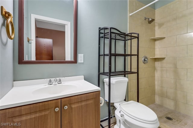 bathroom with toilet, vanity, and tiled shower