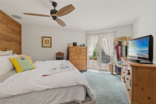 bedroom featuring carpet, wood walls, access to outside, french doors, and ceiling fan