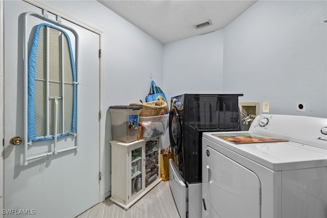 laundry area featuring washer and clothes dryer and light hardwood / wood-style floors