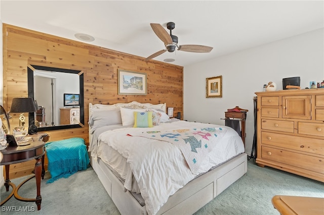 carpeted bedroom with ceiling fan and wooden walls