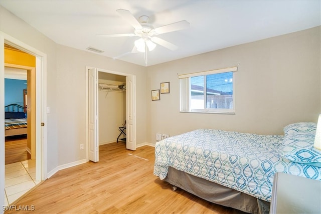 bedroom with ceiling fan, a walk in closet, wood-type flooring, and a closet