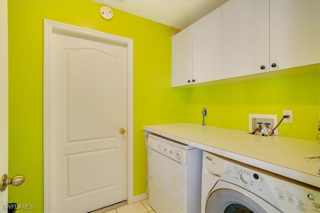 laundry room with washer and clothes dryer, cabinets, and light tile patterned floors