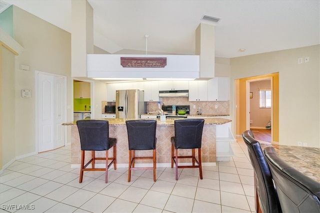 kitchen with white cabinets, stainless steel fridge with ice dispenser, light stone counters, and a kitchen breakfast bar