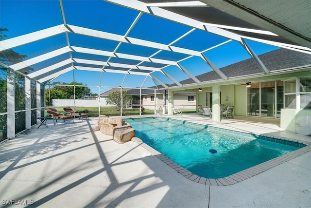 view of pool with glass enclosure, ceiling fan, and a patio area