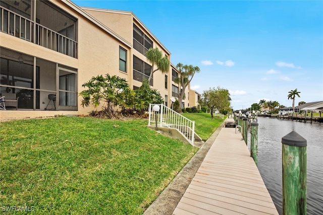 dock area with a water view and a lawn