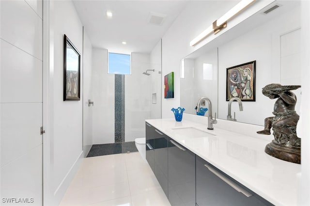 bathroom with vanity, tile patterned flooring, toilet, and a tile shower