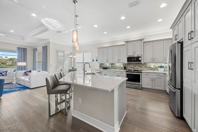 kitchen featuring stainless steel appliances, hardwood / wood-style flooring, a kitchen island with sink, and a breakfast bar