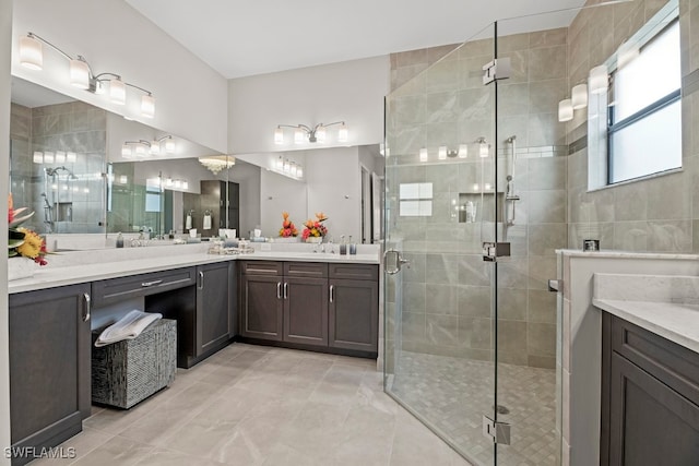 bathroom with a shower with shower door, vanity, and tile patterned flooring