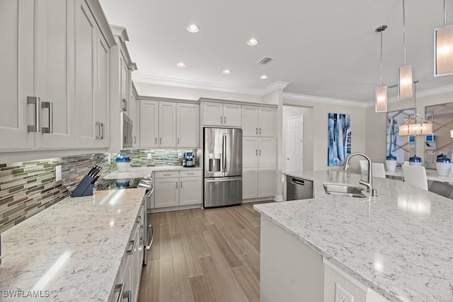 kitchen with stainless steel appliances, sink, light stone countertops, pendant lighting, and light hardwood / wood-style flooring