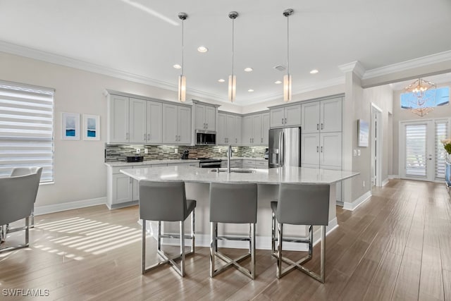 kitchen with hanging light fixtures, sink, a center island with sink, and stainless steel appliances