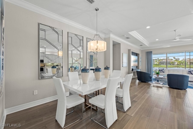 dining space featuring hardwood / wood-style floors, ceiling fan with notable chandelier, a tray ceiling, and ornamental molding