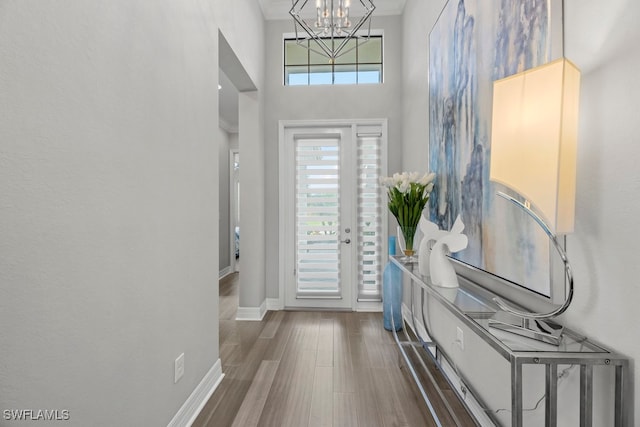 entryway with dark wood-type flooring, a towering ceiling, and a chandelier