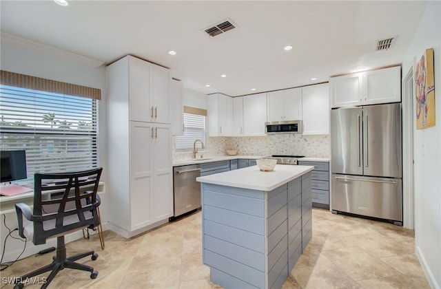 kitchen with tasteful backsplash, stainless steel appliances, a kitchen island, sink, and white cabinets