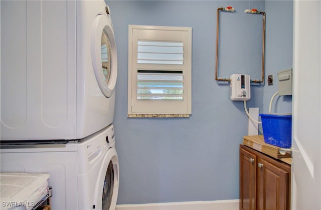 washroom featuring stacked washer / drying machine and cabinets