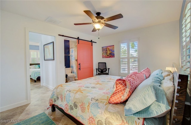 bedroom with a barn door, light tile patterned floors, ceiling fan, and ensuite bath