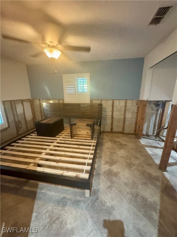 basement with ceiling fan and a textured ceiling