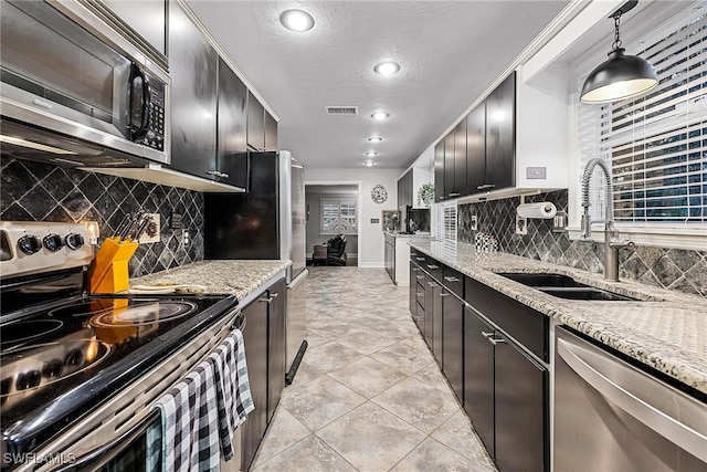 kitchen featuring a textured ceiling, sink, backsplash, pendant lighting, and appliances with stainless steel finishes