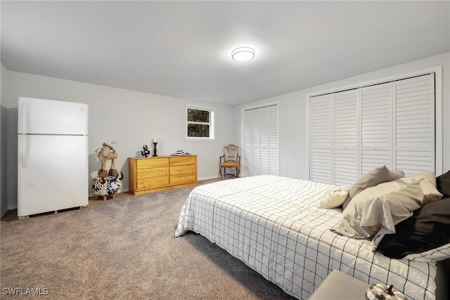 bedroom featuring carpet flooring, white fridge, and two closets