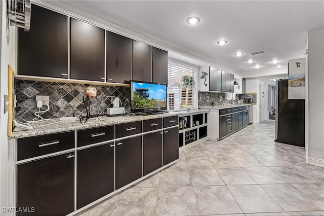 kitchen with sink, light stone counters, backsplash, and light tile patterned flooring