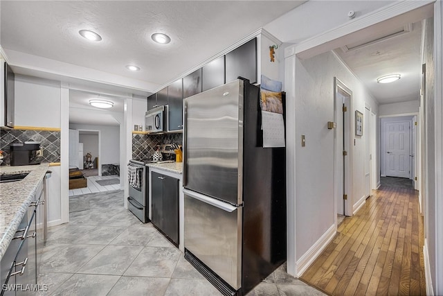 kitchen with tasteful backsplash, light stone countertops, light hardwood / wood-style floors, and stainless steel appliances