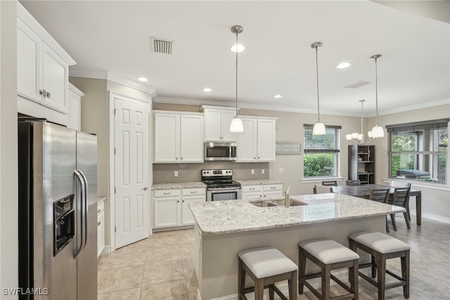 kitchen with a center island with sink, hanging light fixtures, sink, white cabinetry, and appliances with stainless steel finishes