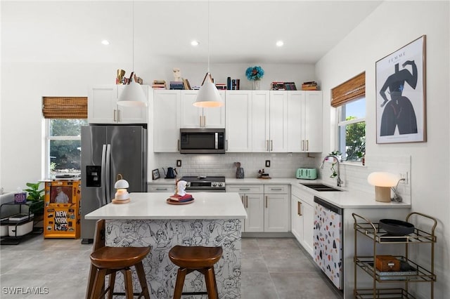 kitchen featuring white cabinetry, sink, stainless steel appliances, a kitchen breakfast bar, and pendant lighting