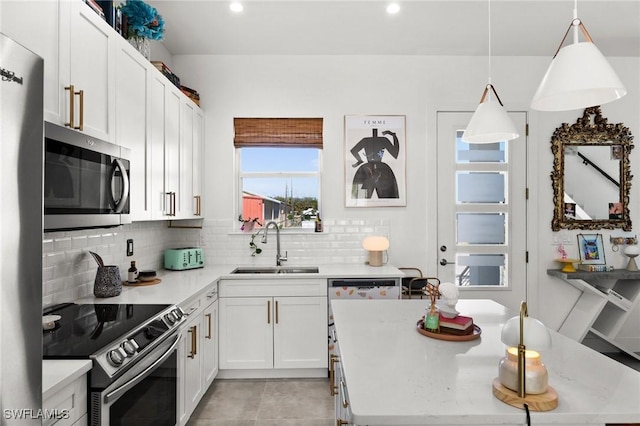 kitchen featuring white cabinets, sink, decorative backsplash, decorative light fixtures, and stainless steel appliances