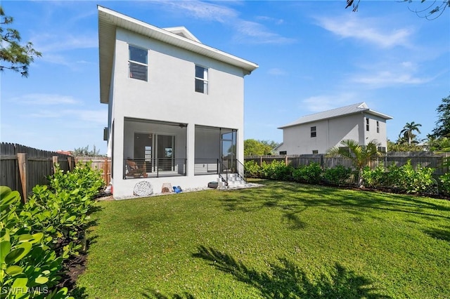 rear view of property featuring a yard and a sunroom