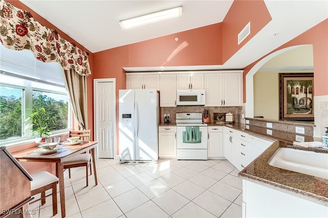 kitchen with white appliances, tasteful backsplash, sink, high vaulted ceiling, and light tile patterned floors