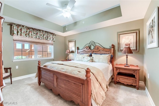 carpeted bedroom with ceiling fan and a raised ceiling