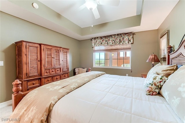 bedroom with ceiling fan and a tray ceiling