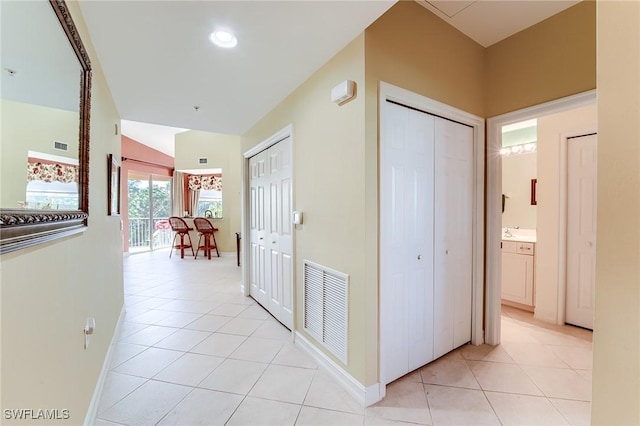 corridor with lofted ceiling, light tile patterned floors, and sink