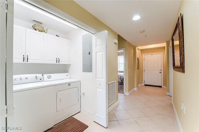 laundry area with light tile patterned floors, electric panel, washing machine and clothes dryer, and cabinets