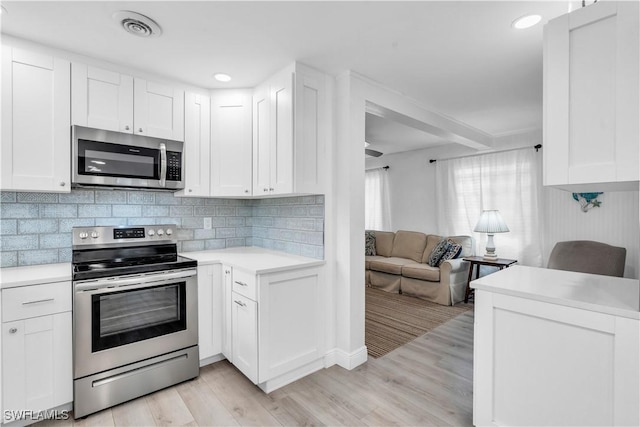 kitchen with stainless steel appliances, light countertops, visible vents, backsplash, and white cabinets