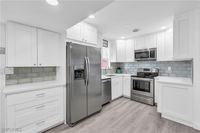 kitchen featuring light countertops, appliances with stainless steel finishes, light wood-type flooring, and white cabinetry